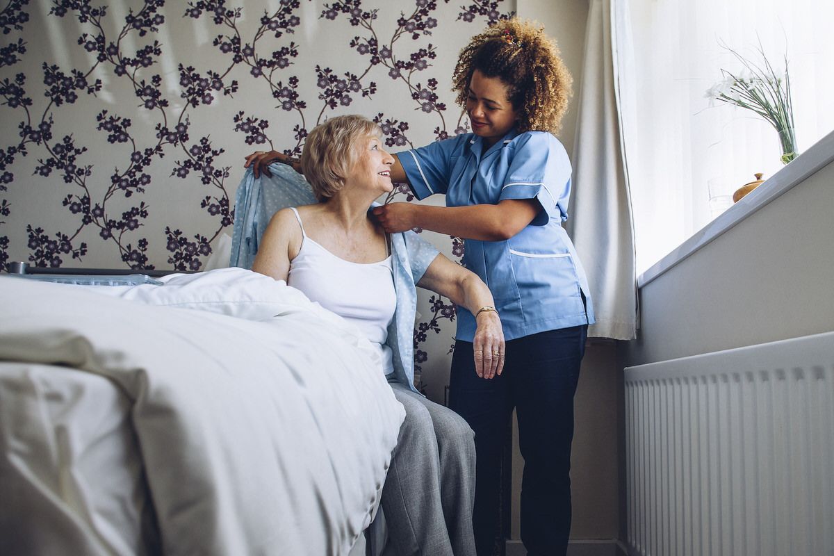 Caregiver helping dress senior