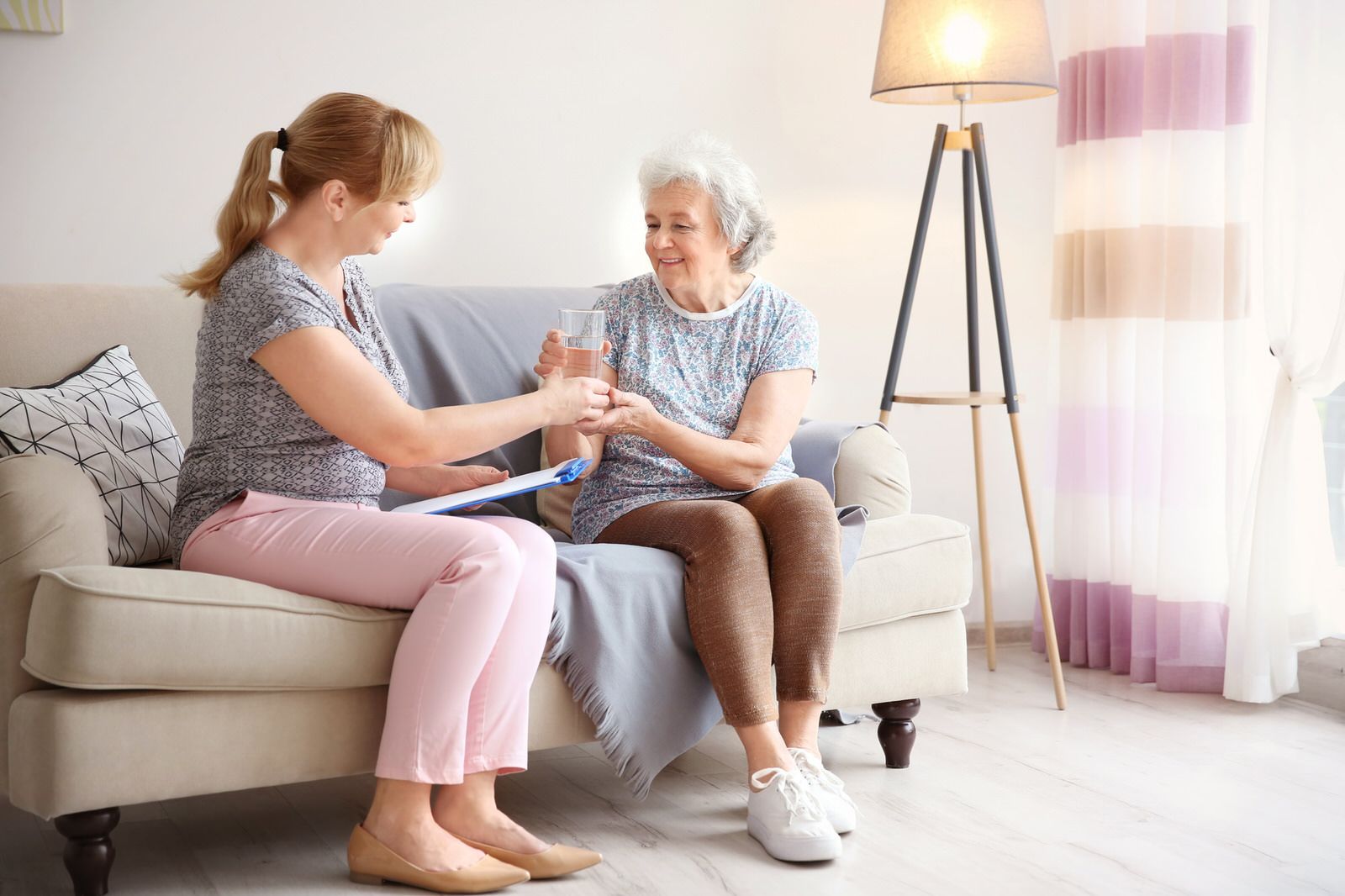 Caregiver giving senior water